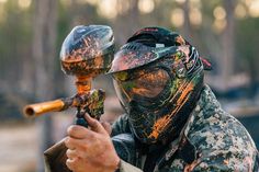 a man in camouflage paint holding a paintball