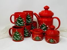 a red tea set with christmas trees painted on it