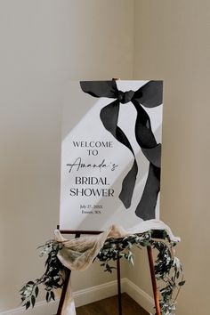 a welcome sign with black and white ribbons on it sitting in front of a wall