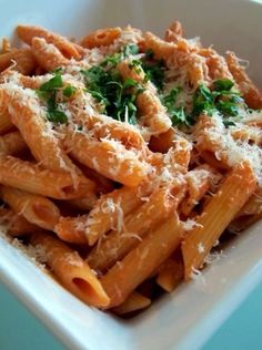 pasta with parmesan cheese and herbs in a white bowl on a blue table