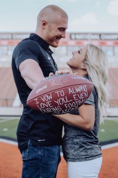 a man and woman standing next to each other holding a football