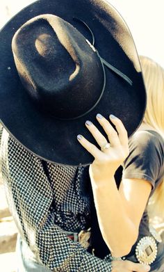 a person wearing a cowboy hat with their hand on the back of his head,