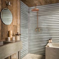 a bathroom with a sink, mirror and bathtub next to a corrugated wall behind it