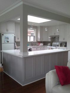 a kitchen with white cabinets and an island in the middle of the living room area