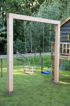 a wooden swing set in the grass next to a house