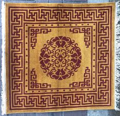 a yellow and red rug with an intricate design on the center, surrounded by fringes