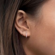 a close up of a woman's ear with two small gold hoop earrings on it