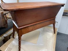 an old wooden desk sitting on top of a piece of plastic in the middle of a room