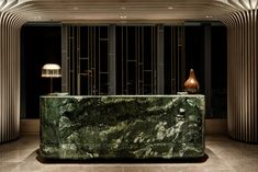 a green marble counter sitting in the middle of a room with lamps on either side