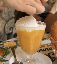 a person scooping ice cream into a glass on top of a white and yellow plate