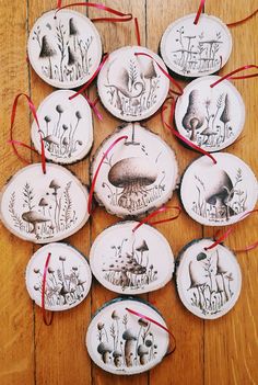 several ceramic ornaments are arranged on a wooden table with red ribbon around them and an image of mushrooms in the woods