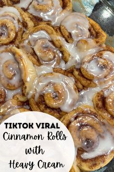 cinnamon rolls with heavy cream frosting in a glass dish on top of a table