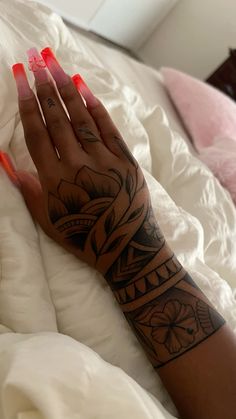 a woman's arm with tattoos on it and her hand resting on the bed