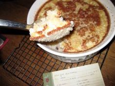 a white bowl filled with food on top of a wooden table next to a note