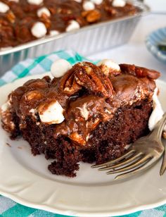 a piece of chocolate cake with marshmallows on it and a fork next to it