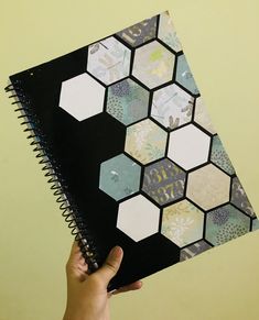 a hand holding a notebook with hexagonal tiles on it