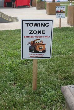 a sign in the grass that says towing zone birthday guests only with cars on it