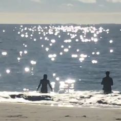 two people are wading in the water at the beach