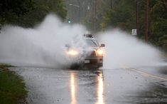 a car driving down the road with it's headlights on and water spraying out