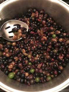 a metal bowl filled with black olives and green olives next to a silver spoon