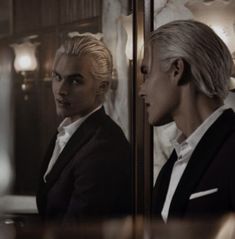 two men in suits looking at themselves in a mirror