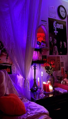 a bedroom with purple lighting and pictures on the wall, candles in front of bed