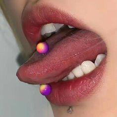 a woman's tongue with rainbow colored balls on the tip of her tongue and white teeth