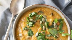 a bowl filled with soup and garnished with cilantro, parsley and peanuts