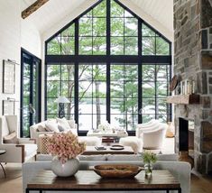 a living room filled with furniture and a stone fireplace in front of a large window