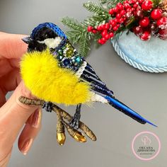 a small yellow and blue bird sitting on top of a tree branch next to a potted plant