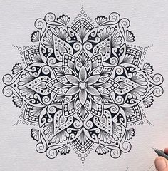 a drawing of a black and white flower design on paper with marker pens in front of it