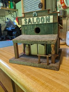 a wooden birdhouse sitting on top of a table next to a sign that says saloon