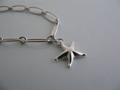 Overview:Offered for sale is a wonderful and gorgeous Tiffany and Co. Sterling Silver Peretti Starfish Link Bracelet. The piece is made from bright Tiffany sterling silver, yet has a very delicate and feminine feel to it. Hanging from its Tiffany Sterling Silver link chain is a whimsical and very pretty starfish. The piece is quite hard to find and come by, so grab it while you have the chance! It is very pretty worn on its own, but would also work very well with other jewelry that you already o Elegant Starfish Bracelet For Gift, Silver Starfish Bracelet For Gift, Silver Starfish Bracelet, Silver Link Chain, Tiffany And Co, Gift Pouch, Bracelet Bangle, Tiffany & Co., Link Chain