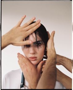 a woman holding her hands up to her face with both hands on top of her head