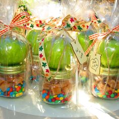 some green apples are in plastic bags on a table with candies and other items