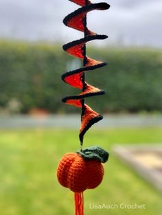 a crocheted wind chime with an orange hanging from it's side