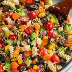 a colorful pasta salad with tomatoes, broccoli, olives and other vegetables