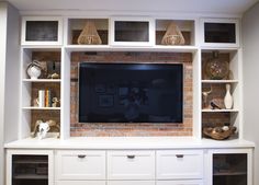 an entertainment center with built in shelves and a flat screen tv mounted on the wall