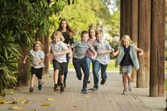 a group of young children running down a sidewalk