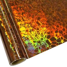 a roll of shiny metallic foil on top of a white surface with an orange, yellow and green pattern