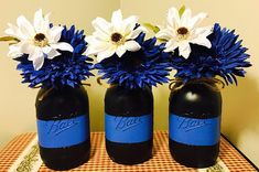 three blue and white vases with flowers in them sitting on a checkered table cloth