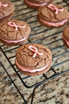 chocolate cookies with pink frosting and bows on a cooling rack, ready to be baked