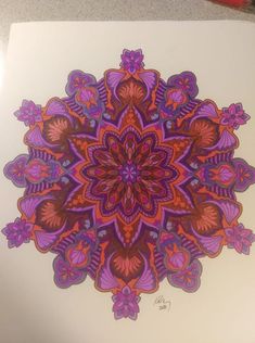 a drawing of a purple and red flower on paper with colored pencils next to it