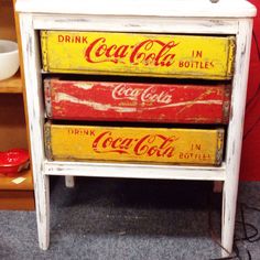 three coca - cola crates stacked on top of each other in front of a red wall