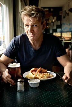 a man sitting at a table in front of a plate of food and a beer