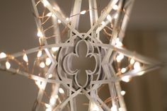 a star shaped light fixture with white lights on the sides and an intricate design in the middle