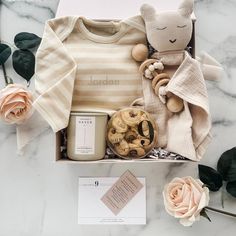 the baby gift box contains an infant's bodysuit, rattlers and cookies