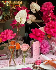 pink and white flowers in vases on a table with napkins, plates and utensils