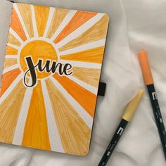 an open notebook with the word june written on it and two markers next to it