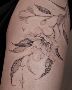 a woman's thigh with flowers and leaves on the side, in black and white